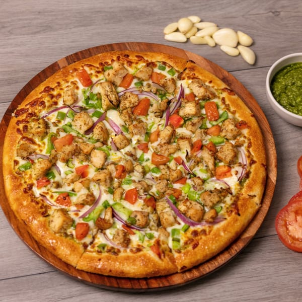 Can Am Pizza's chicken pizza with tomatoes, red onions, and green peppers on a wooden board.
