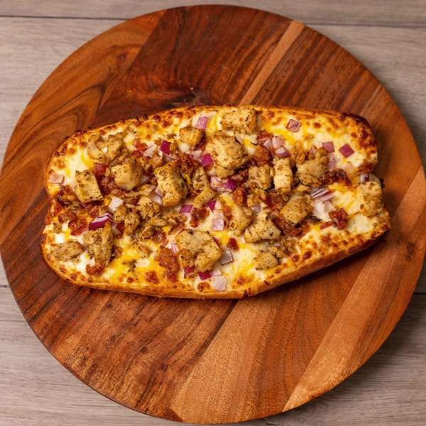 Can Am Pizza's chicken, bacon, and red onion pizza bread on a wooden serving board.