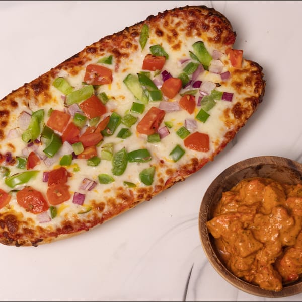 Can Am Pizza's cheesy bread with diced tomatoes, green peppers, and red onions, next to a bowl of butter chicken.
