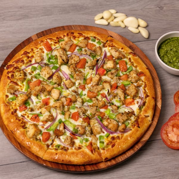 Can Am Pizza's chicken pizza with red onions, green peppers, and tomatoes on a wooden board.