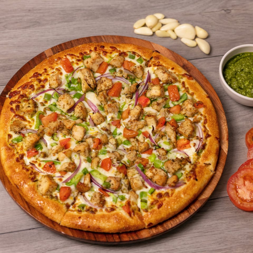Can Am Pizza's chicken pizza with red onions, green peppers, and tomatoes on a wooden board.