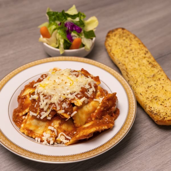 Can Am Pizza's ravioli with red sauce and cheese, served with a side salad and garlic bread.