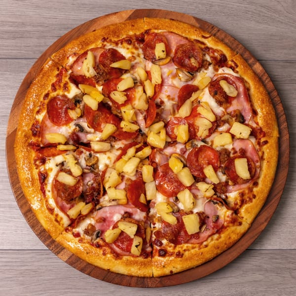 Can Am Pizza's pepperoni, ham, mushroom, and pineapple pizza on a wooden serving board.