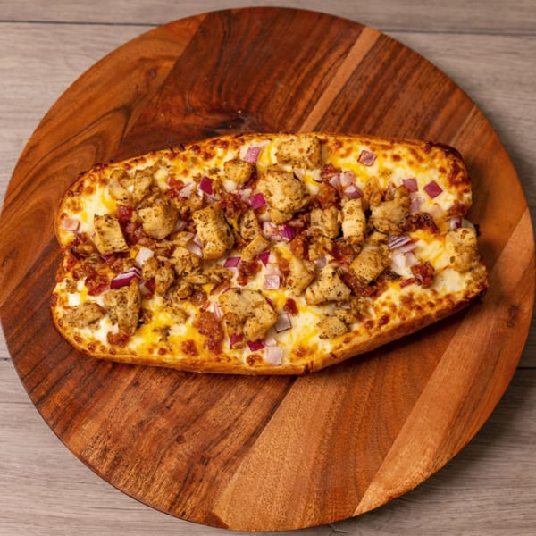 Can Am Pizza's chicken and bacon pizza bread with red onions on a wooden serving board.