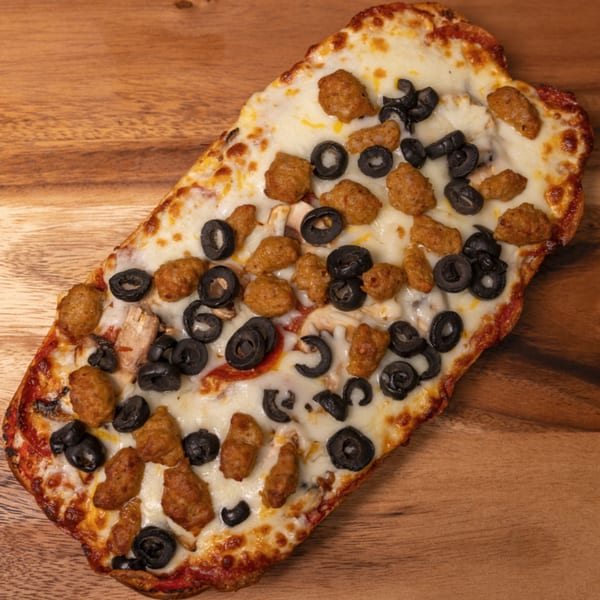 Can Am Pizza's rectangular pizza with melted cheese, sausage, and black olives on a wooden board.